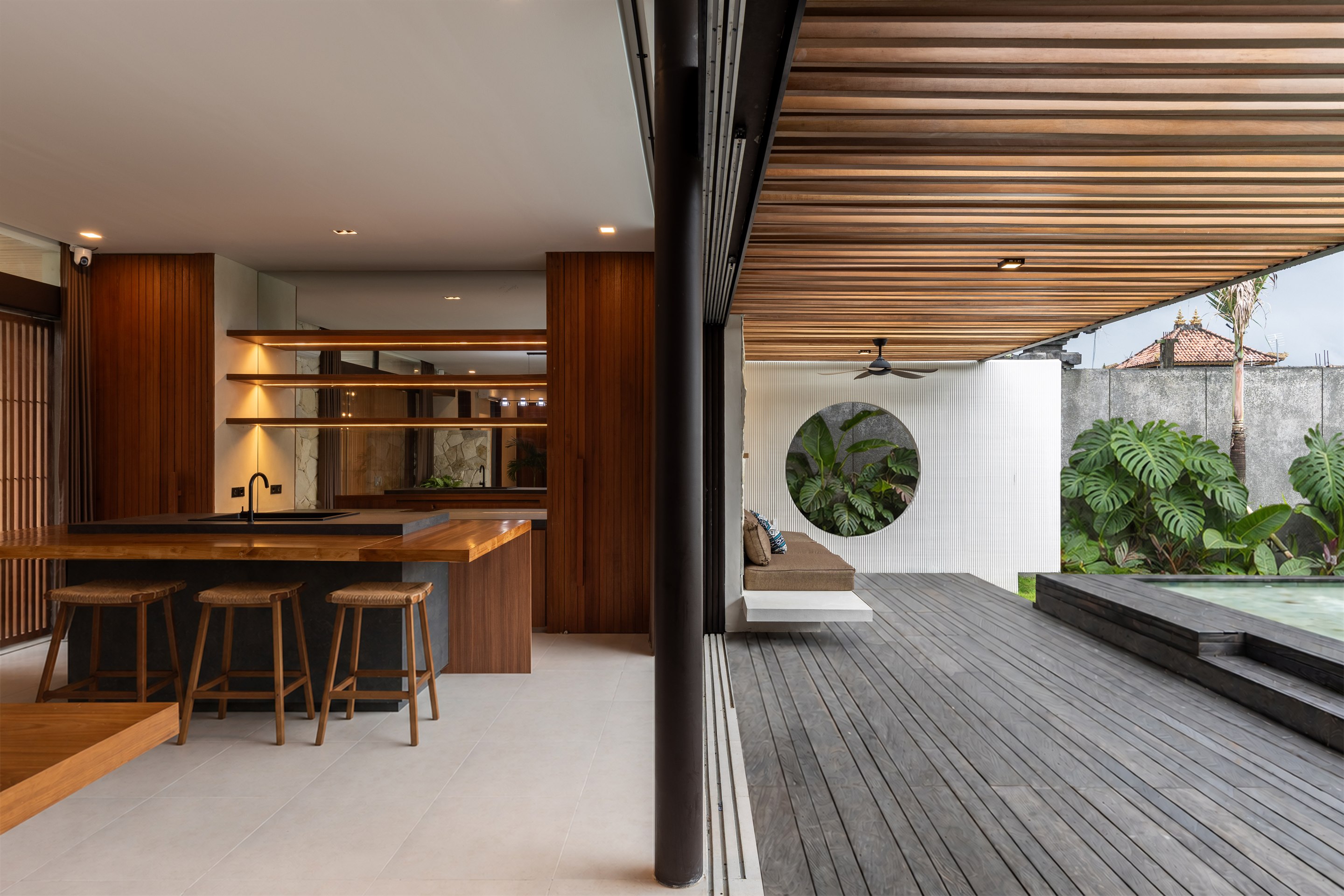 Batuan Villa open-plan kitchen, timber deck, pool, and tropical garden.
