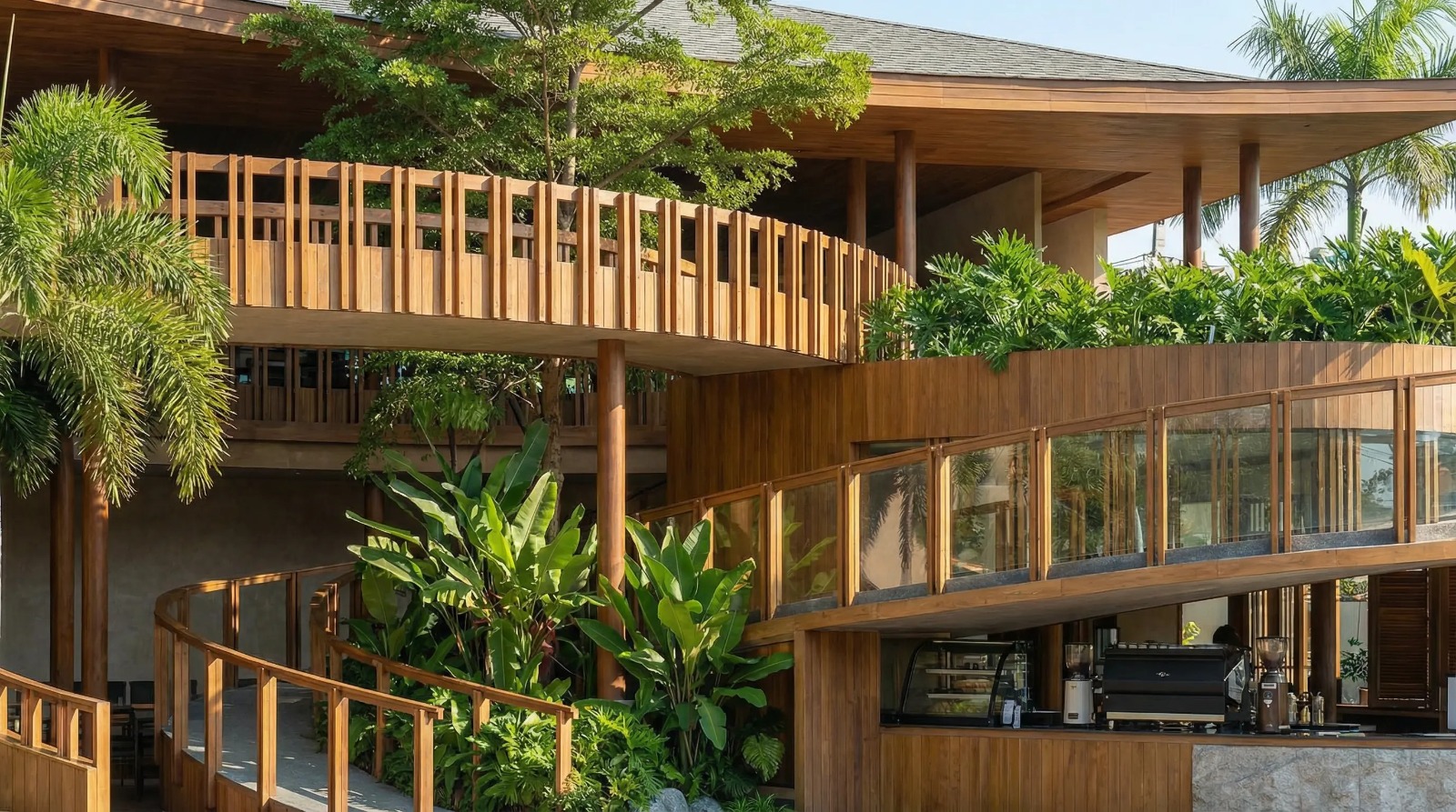 Layered tropical restaurant architecture with timber walkways and garden planting.